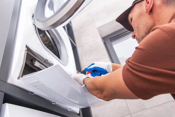 A Technician at House Repairs a Washing Machine Dryer in Keller, TX